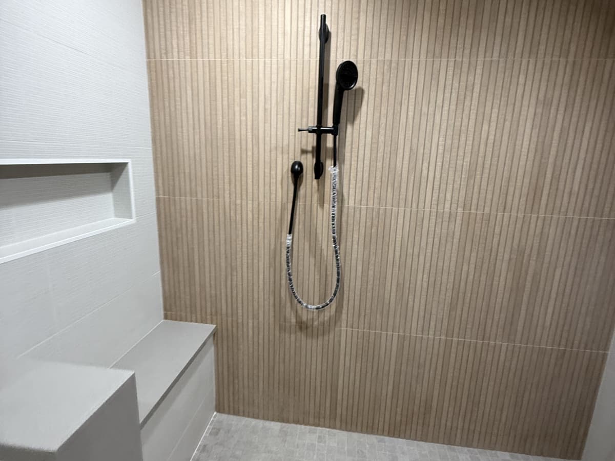 A finished walk-in shower with warm fluted tile, a built-in bench and a recessed niche