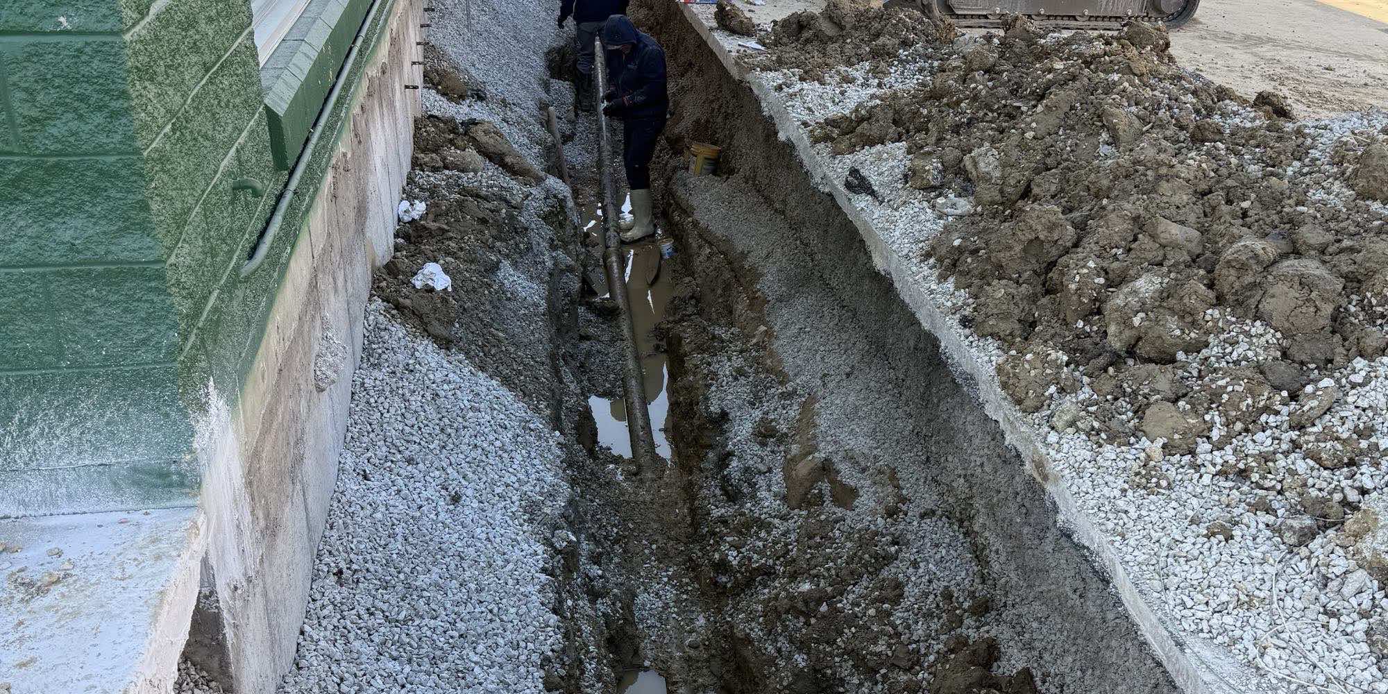 A trench excavated alongside a commercial building for a new underground service line