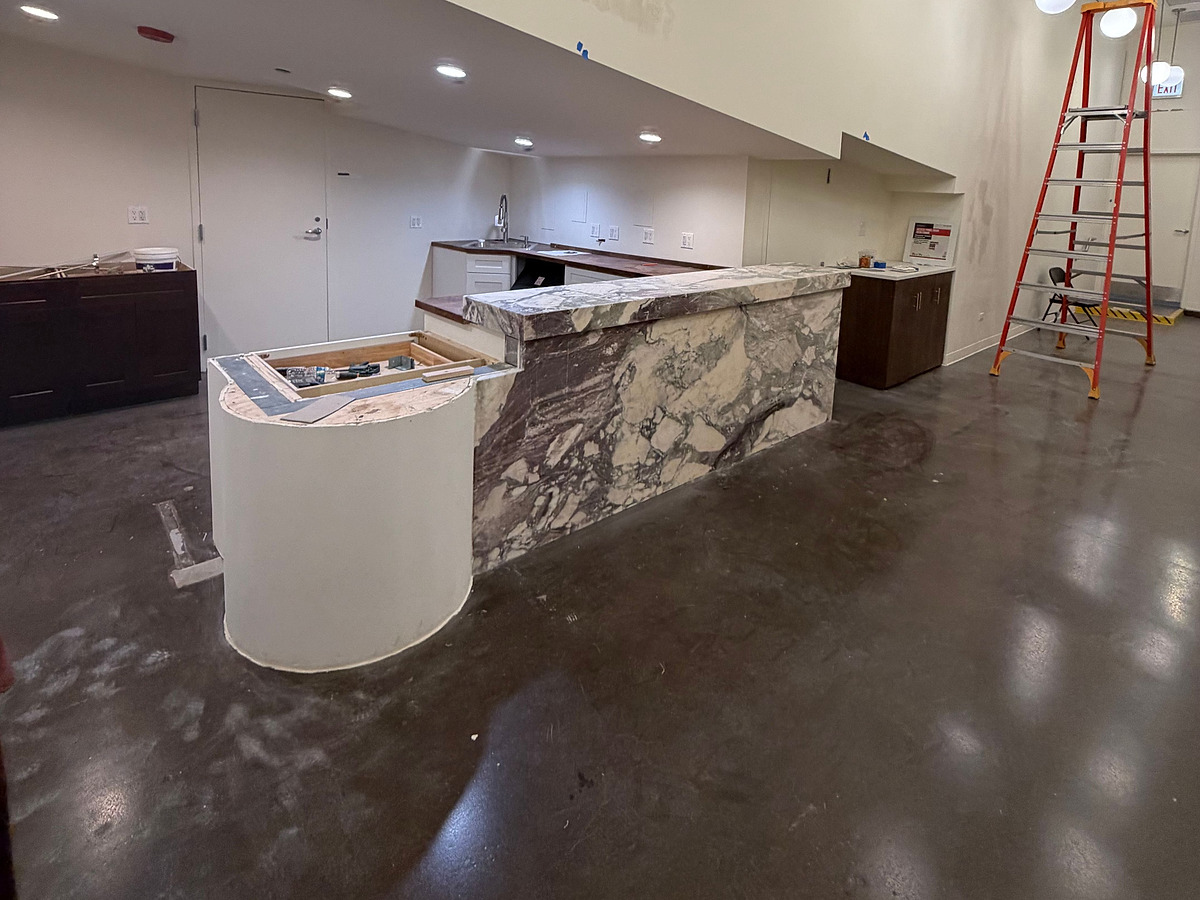 A marble cafe counter part-built, with the stone set and the surrounding millwork and floor still unfinished
