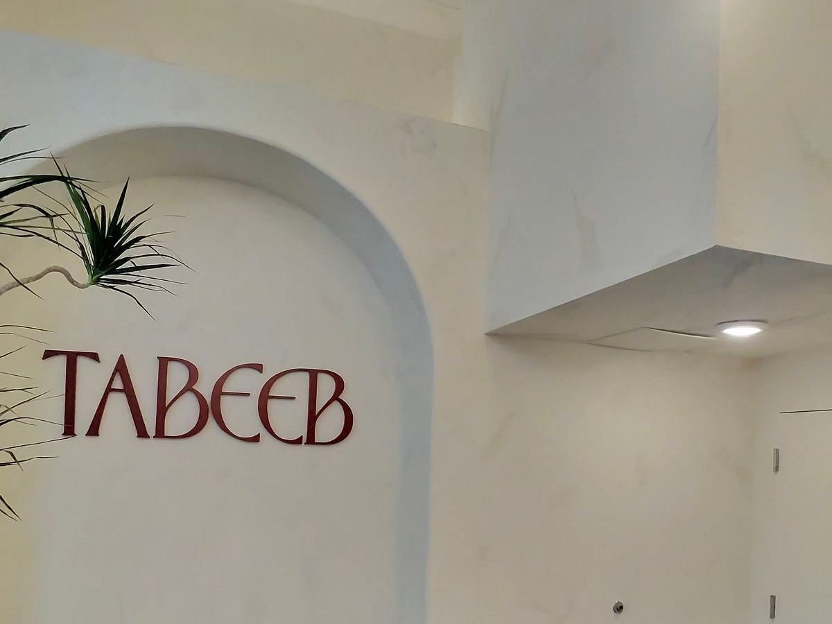 The cafe name in dark red lettering mounted on a hand-plastered arched recess above a built-in bench
