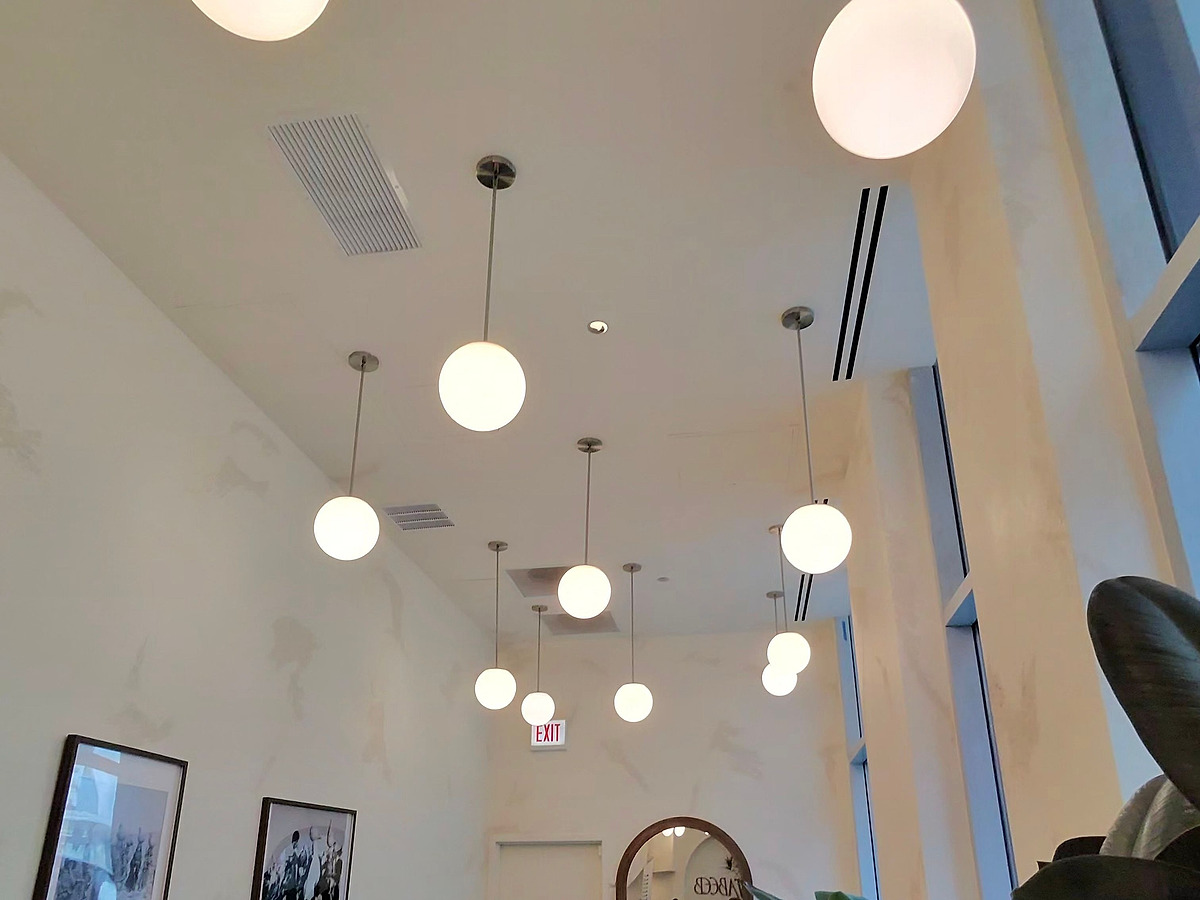 The double-height plastered ceiling of the cafe, hung with a scattered constellation of white globe pendants