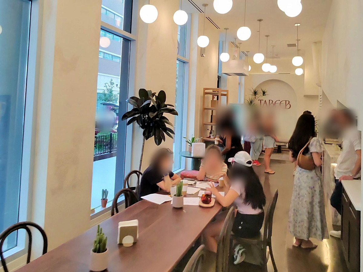 A long communal walnut table running down the cafe's window wall under full-height glazing